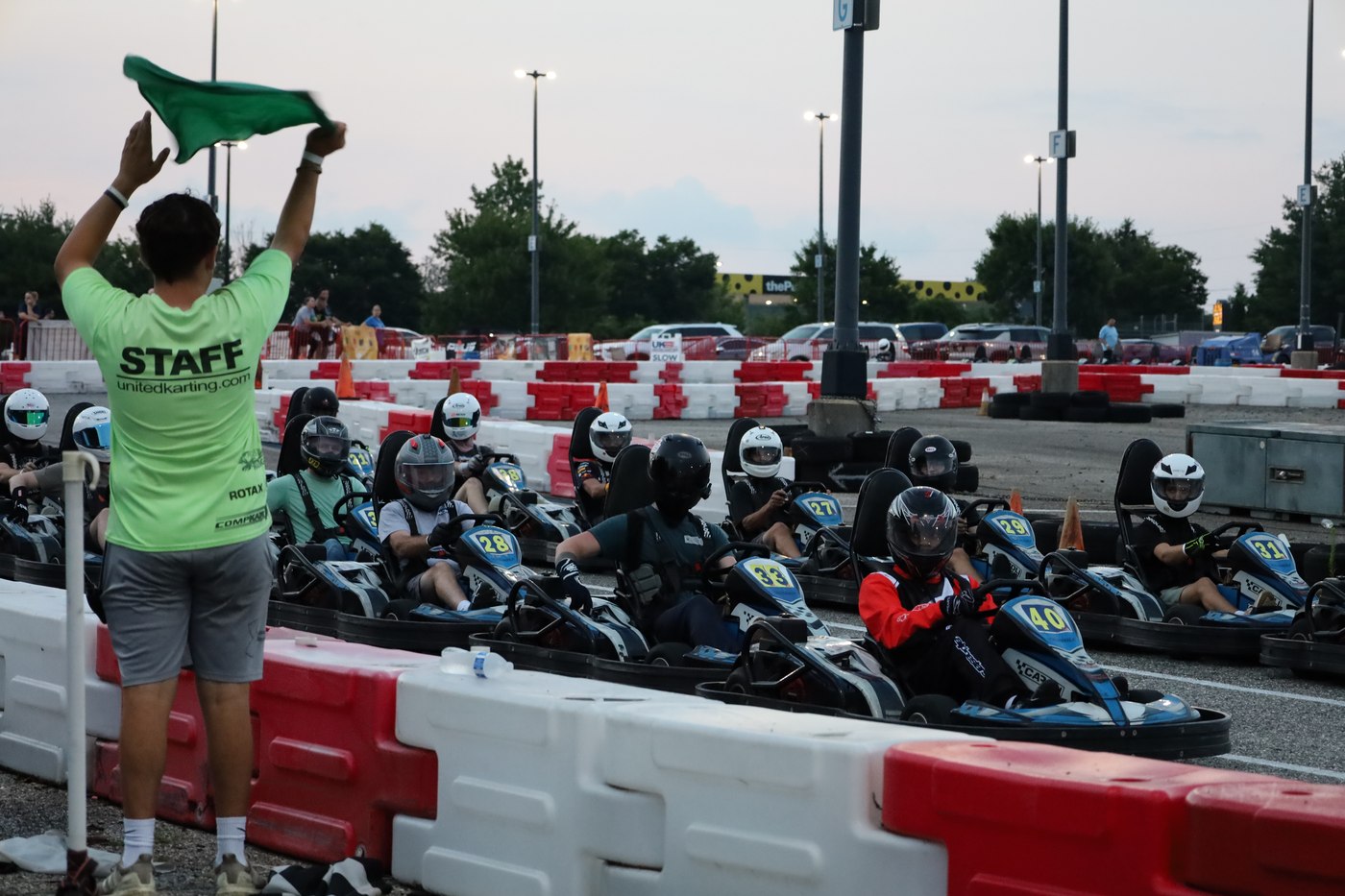 A race staff member waving the green flag to start a heat of go-karts
