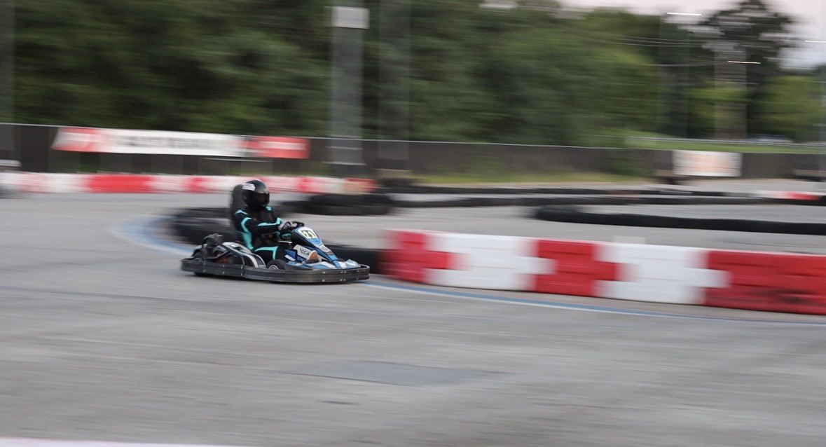 A go-kart racing mid-turn, motion-blurred track behind it